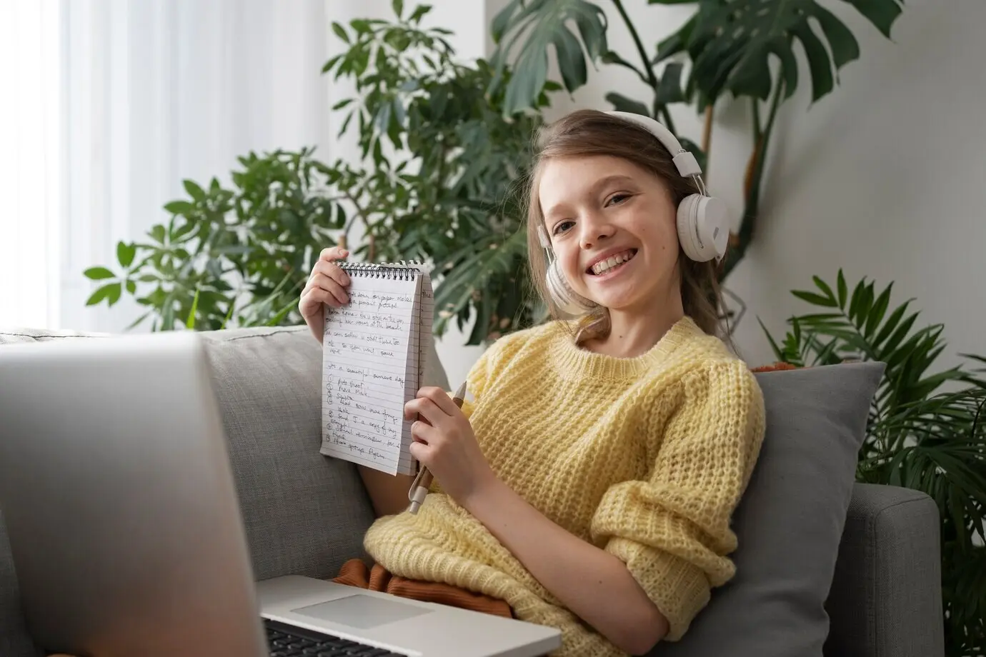 Вид сбоку улыбающейся девушки, держащей ноутбук.